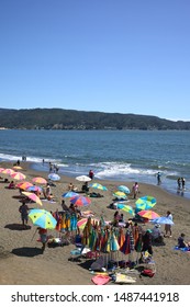 NIEBLA, CHILE - FEBRUARY 2, 2016: Parasol rental and visitors enjoying the sun and the water on the sandy beach of Niebla, Chile on February 2, 2016. Niebla is a small town on the Pacific coast.