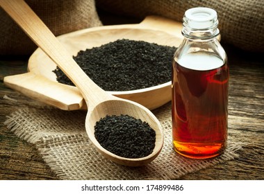 Nigella sativa (Black cumin) on wooden spoon and essential oil. Real oil from nigella looks like dark honey - Shutterstock ID 174899486