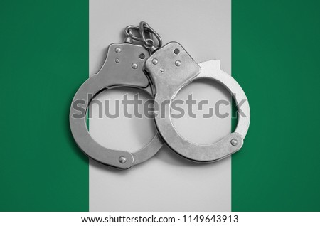 Nigeria flag  and police handcuffs. The concept of observance of the law in the country and protection from crime