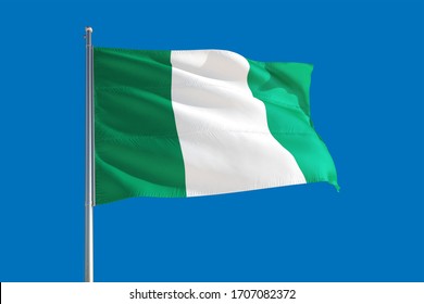 Nigeria national flag waving in the wind on a deep blue sky. High quality fabric. International relations concept.