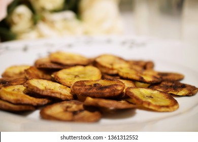Nigerian plantain chips in plate with blurred flower background on table