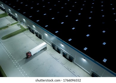 Night Aerial top view of truck and cargo trailer unloading in logostics center.