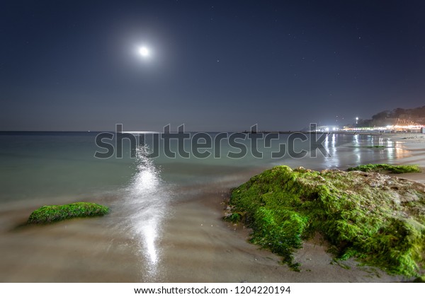 Night Black sea landscape in Odessa with moon\
reflection and colored\
stones