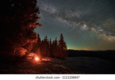 Night Camping. Man And Woman Friends Resting Near Night Bonfire During Mountaineering Vacations For Visiting Ukrainian Nature Environment, Boyfriend And Girlfriend Have Wild Journey For Trekking