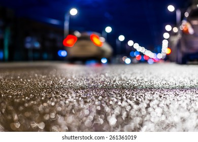 Night City After Rain, The Car Driving On The Road. Close Up View From Asphalt Level, In Blue Tones