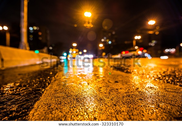 Night city\
after rain, the glowing lights of approaching cars. Wide angle view\
of the level of the pedestrian\
crossing