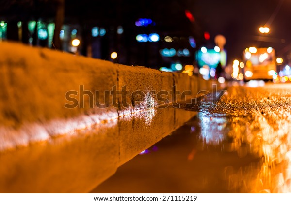 Night city after rain, a reflection of the city at\
night in the water. View of the driving bus from the roadside at\
the asphalt level