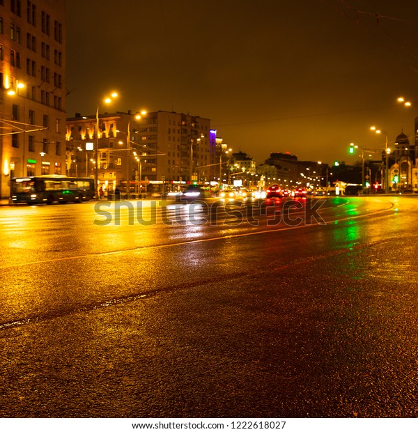 Night city lights in the rain. Cars in motion\
and blurred. Outdoor\
lighting.
