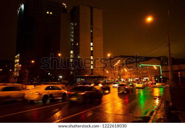 Night city lights in the rain. Cars in motion\
and blurred. Outdoor\
lighting.