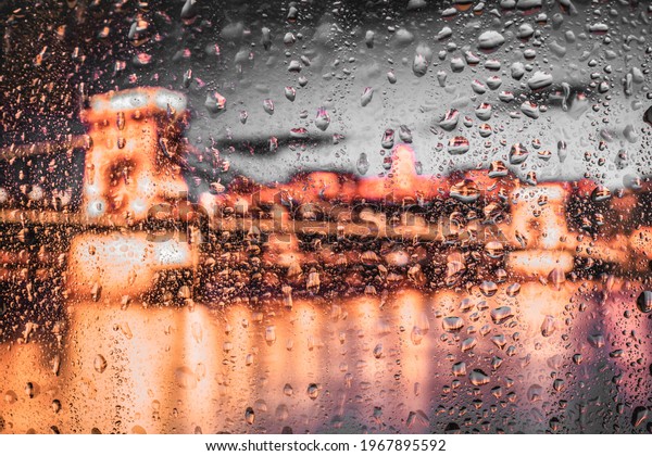 Night city lights through window with\
rainwater and drops. Background with\
bokeh.