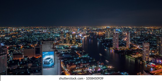 Night city scape view from Lebua Sky Bar - December 8, 2014: Bangkok, Thailand. Panorama overlooking the Chao Phraya River with city skyline from hotel Lebua at State Tower at night.