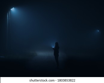 Night City In A Thick Wet Fog . Film Grain And Noise. Silhouette Of A Girl With A Flashlight Walking Along The Road At Night. 