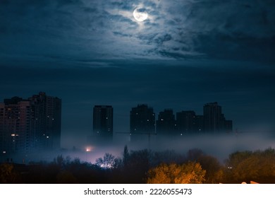 Night cityscape. The full moon through the clouds over city street at night with high modern buildings among the fog with illumination from a street light. Blackout in Kyiv. Ukraine. - Shutterstock ID 2226055473