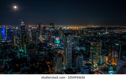 Night cityscape view from Lebua Sky Bar - December 8, 2014: Bangkok, Thailand. Night panorama of Bangkok with full moon from luxury hotel Lebua at State Tower. Bangkok city scape nightlife photo.
