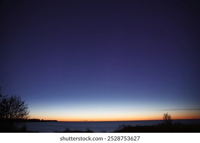 Vista do céu clara da noite com inícios e pôr do sol tardio no horizonte, costa do mar