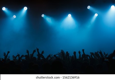 Night Club Dj Concert Crowds Waving Hands In Blue Stage Lights.Silhouette Of Edm Musical Festival Crowd Partying On Dancefloor.Illuminated Scene In Music Hall.Background For Entertainment Event Poster