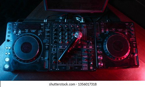 Night club, nightlife concept. Disco. Microphone on DJ remote. Neon red blue light. Top view