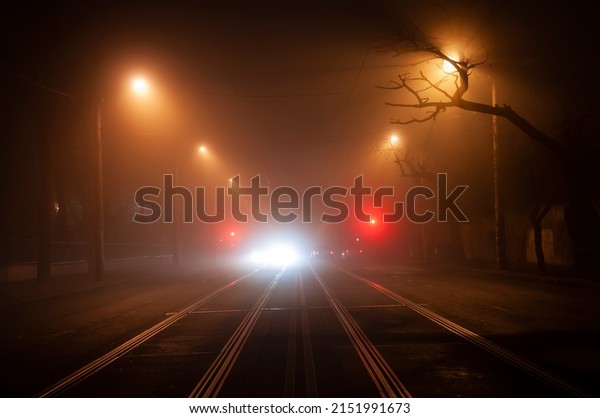 Night deserted street in heavy fog. blurry lights\
of passing cars.
