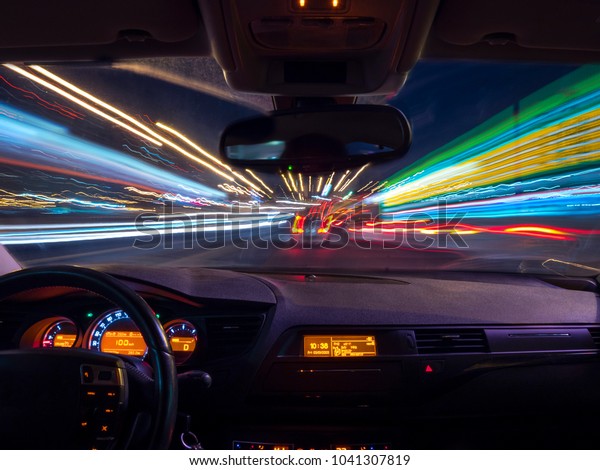 Night driving, view from inside car, city and\
other cars light is motion\
blurred.