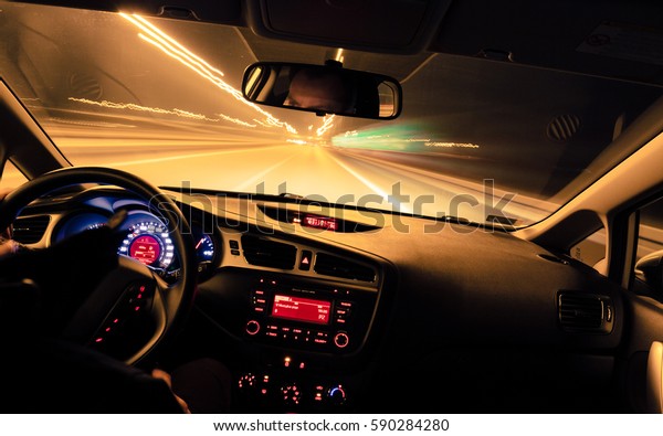 Night driving, view from inside car, city and\
other cars light is motion blurred.\
