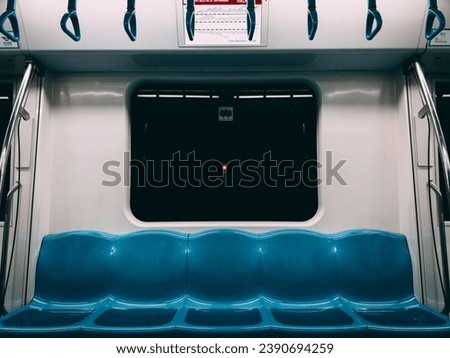 At night, empty blue metro seats, with a dark window above looking outside and a screen displaying the metro line