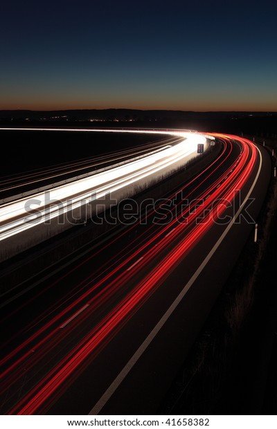 Night highway (Cars in a rush moving fast on a\
highway (speedway) at the\
nightfall