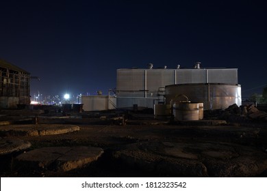 Night image of an old manufacturing building being demolished in the western suburbs of Melbourne, Australia, with the city lights in the background.