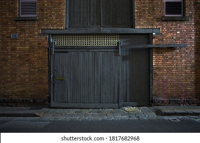Night image of an old weathered stable roller door and brick wall in a laneway in the old Victorian inner suburbs of Melbourne, Australia.