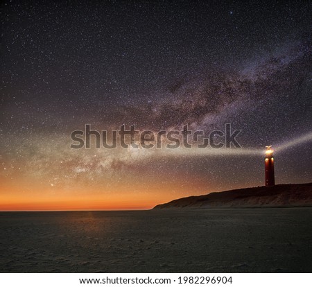 Night image of the Texel lighthouse serving as a navigation beacon for ships with starry nightsky with Milky way galactic core
