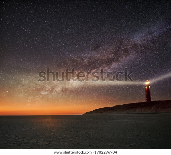 Night image of the Texel lighthouse serving as a\
navigation beacon for ships with starry nightsky with Milky way\
galactic core
