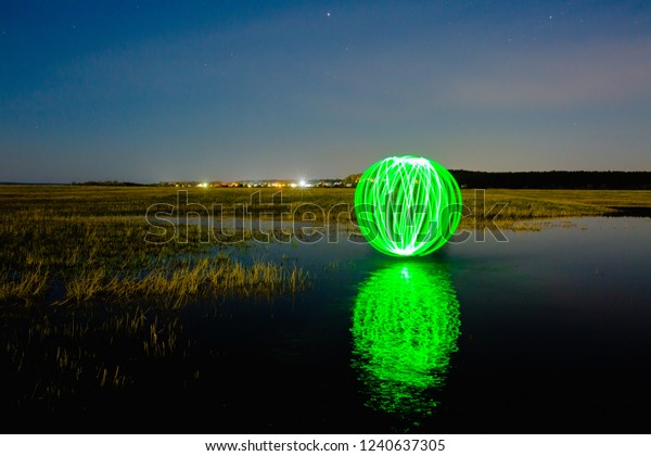 Night landscape with the Futuristic glowing\
sphere reflected on the river\
surface
