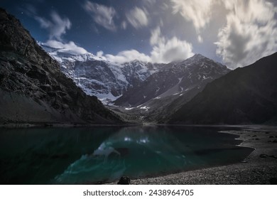 Night landscape of Kulikalon lake and mountain range with rocks, snow and glaciers in the Fan Mountains in Tajikistan, Tien Shan highlands on a starry moonlit night - Powered by Shutterstock