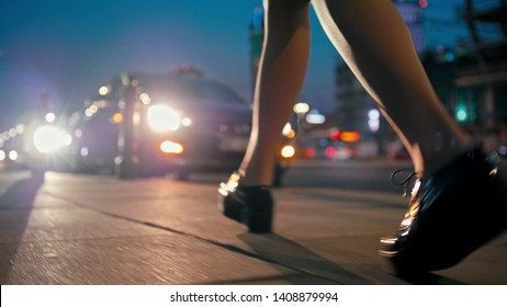 Night Life In The Big City: Close Up Woman Legs In Patent Platform Shoes Walking Along The Street In Town With Blurred Lights At The Background In Late Evening