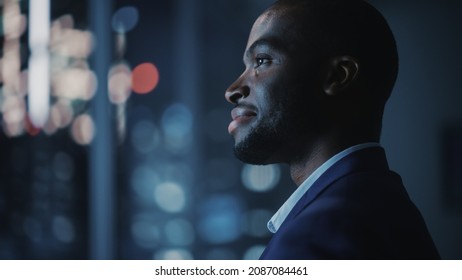 Night Office: Stylish Close-up Portrait of Powerful Black Businessman Wearing Suit Standing, Looking out of the Window on a Big City. Ambitious African CEO Thinking of e-Commerce Investment - Shutterstock ID 2087084461