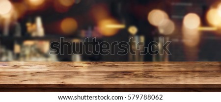 Night panorama with bokeh in a bar in front of an empty wooden table for a solemn concept