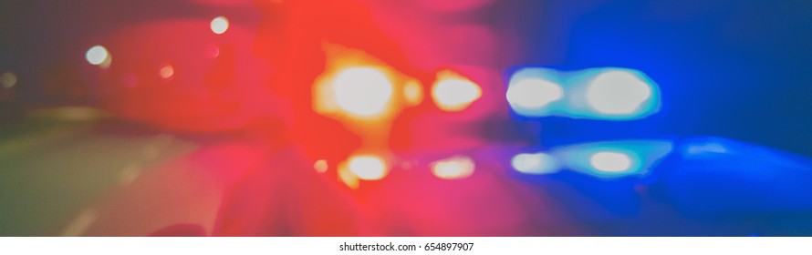 Night Patrolling The City. Red And Blue Lights Of Police Car In Night Time. Abstract Blurry Image.