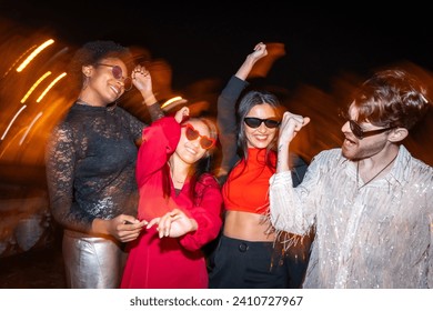 Night photo with flash and motion of a group of excited multi-ethnic friends dancing in the street - Powered by Shutterstock