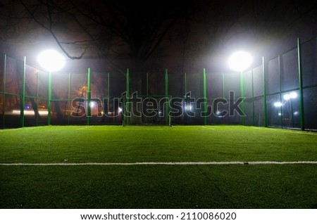 Night photo of a football field in the park. Winter night photography of an artificial football field. Empty gates at night. Mini football field in the light of night lights