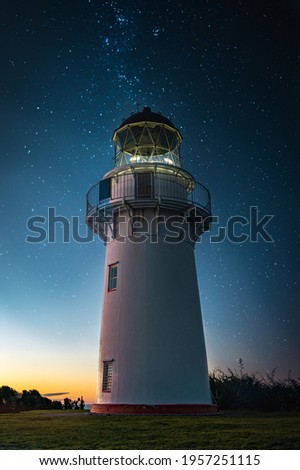 Night photo full of colors with a breathtaking view of the lighthouse, lots of stars in the sky and the setting sun.