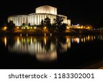 Night photo of a modern "Opera Nova" building in Bydgoszcz, Poland, with a beautiful blurry reflection in the Brda River.  The view shows the river bank, yellow sodium lanterns and white opera house.