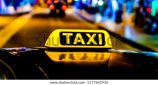Night picture of a taxi car. Taxi sign on the car\
roof glowing in the dark