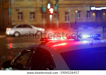 night police car lights in city street with civilian car in blurry background