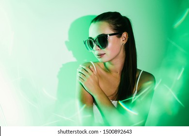 Night Portrait Of A Young Beautiful Girl With Reflection In Sunglasses In Green Neon Light Flashes.