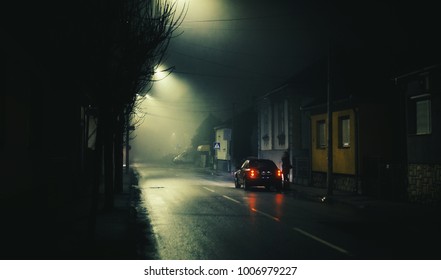 Night Scene On Foggy Street Of A Small Town, Lonely Woman And One Car. 