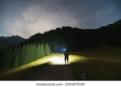 Night scene, the silhouette of a man with a headlamp goes hiking in the Tatra Mountains in summer. High quality photo