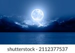 Night sky with big blue moon rises above the sea among the clouds "Elements of this image furnished by NASA"