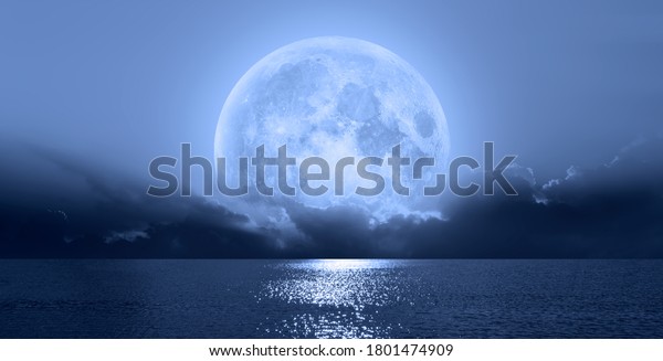 Night sky with blue moon\
in the clouds over the calm blue sea \