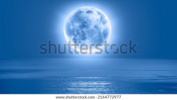Night sky with blue moon\
in the clouds over the calm blue sea \