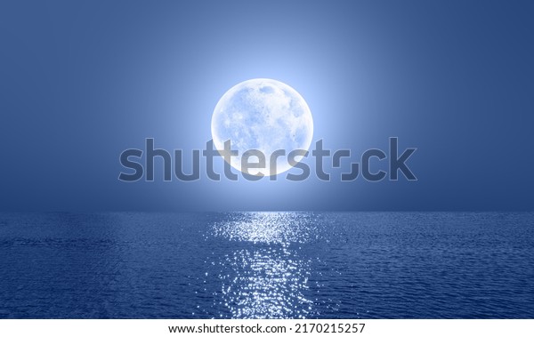 Night sky with blue moon in the clouds over the calm
blue sea, many sytars in the background  