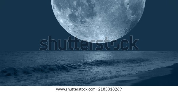 Night sky with blue moon
in the clouds over the calm blue sea 